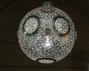 Plafonnier en métal argenté (laiton perforé et ciselé). Allumé, il projette sur les murs des petites taches de lumière.